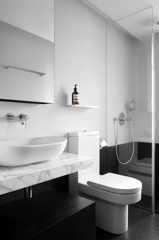 This design takes the linear bathroom to a whole new level. The chair-rail-height tile line that continues through the space emphasizes the length, while also making it feel very open with the bright whites and glass divider.