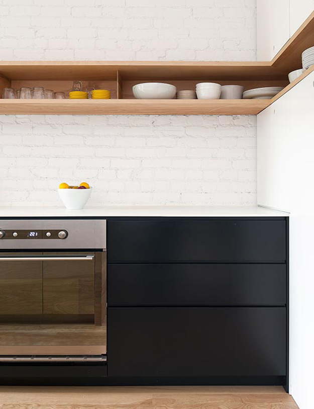 This very simple line of open shelves turns the corner into a set of built-in cabinets which is a glorious detail to its own, made even better by the bright whites of the brick wall turning the corner on the counter and topping a row of modern, dark cabinets. #ThisOldHouse kitchen inspiration via www.L-2-Design.com